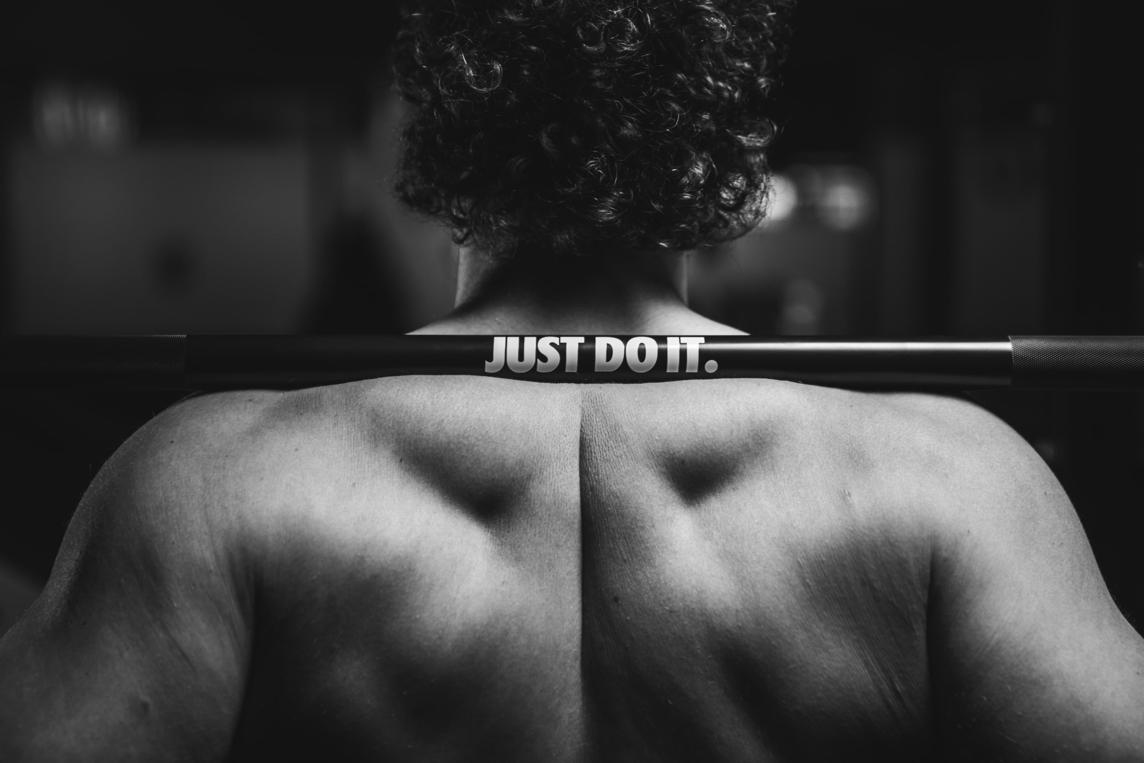 An athlete under a barbell, photographed in black and white