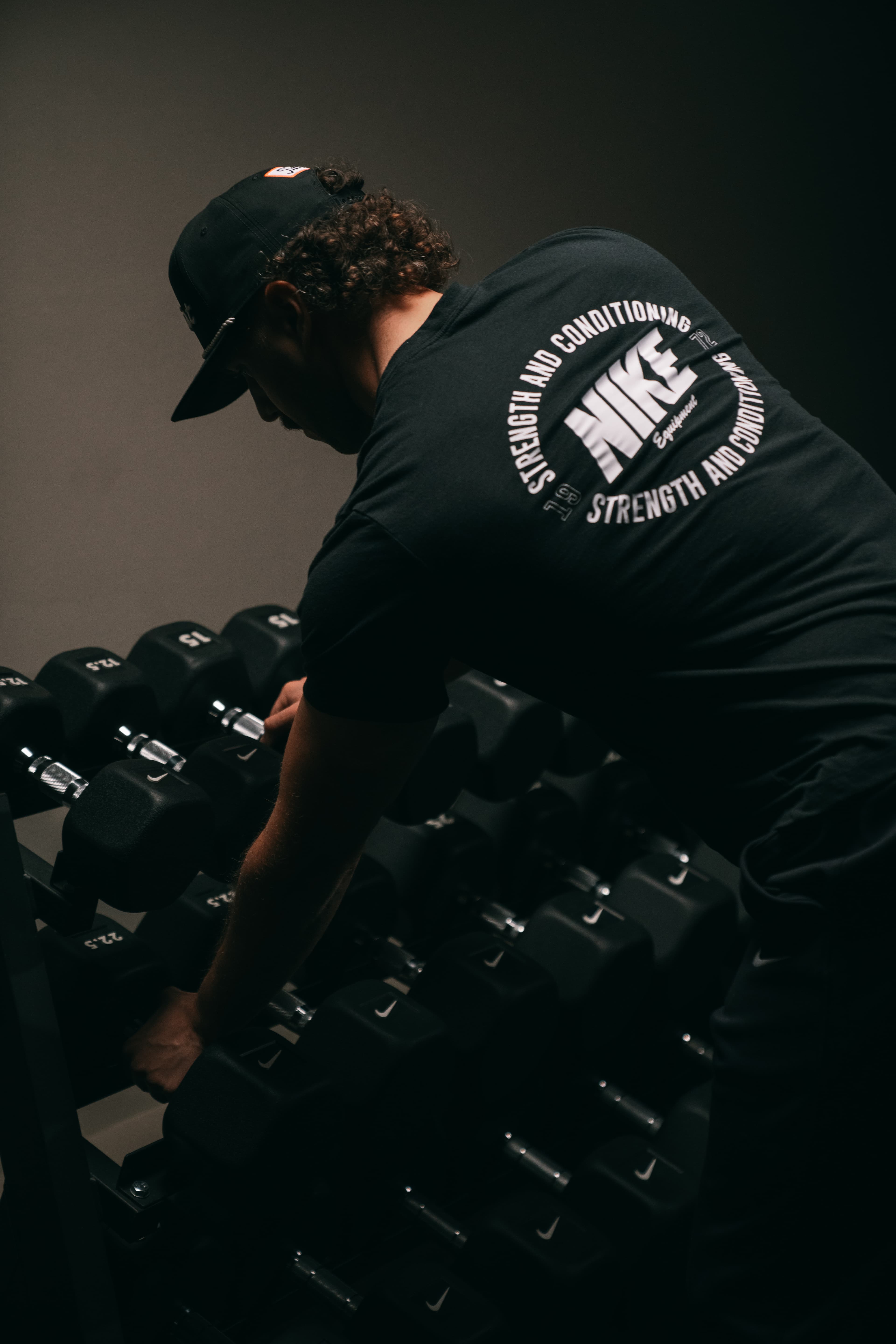 A coach setting up the dumbbell rack